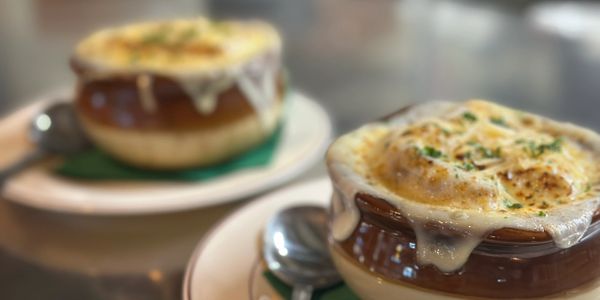 Two bowls of French onion soup with melted cheese on top.