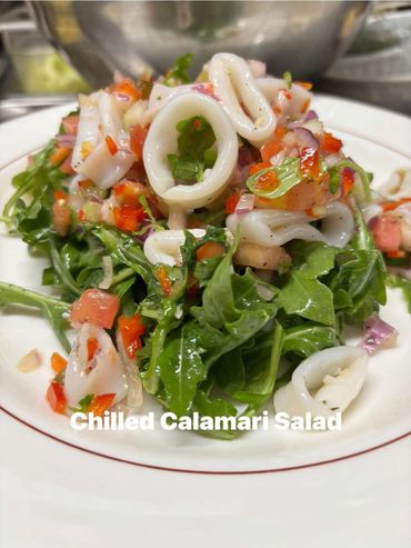 Fresh chilled calamari salad with arugula and diced vegetables.