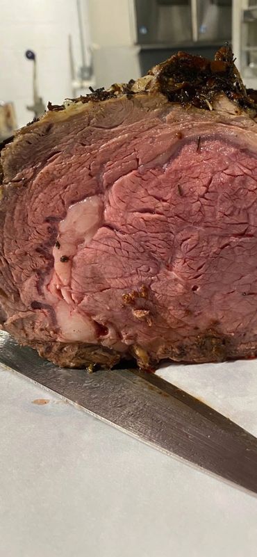 Close-up of a juicy, sliced roast beef with herbs on top.
