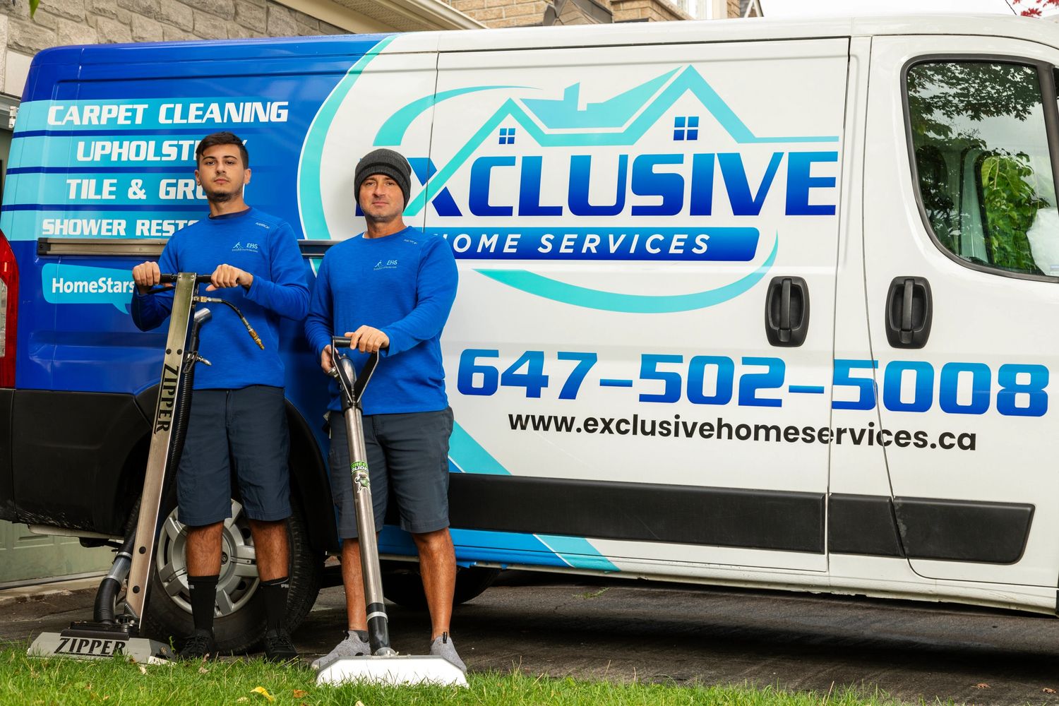 Two carpet cleaning professionals in blue uniforms stand with equipment by a branded service van.