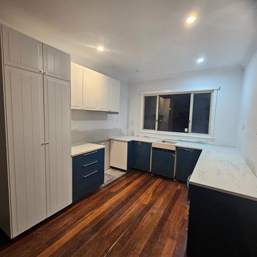 A sleek transformation: dark navy kitchen with marble benchtop and spacious pantry modern style