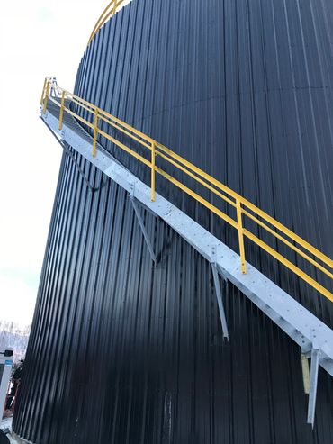 Metal staircase with yellow railing on black silo.