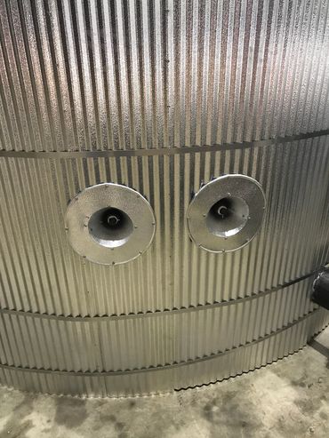 Two circular metal vents on a corrugated metal surface.