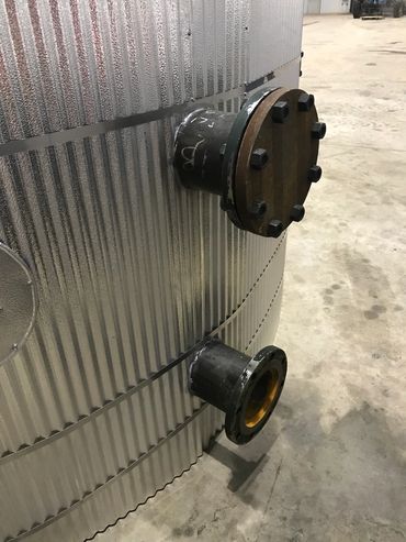 Metal tank with two pipe connections in a warehouse.