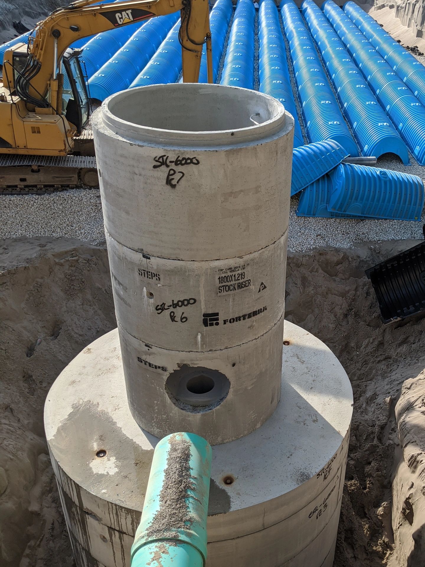 Construction site with large concrete pipes and blue stormwater chambers.