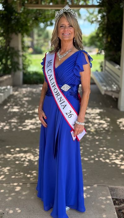 Woman wearing a blue gown and Ms. California sash with a crown.