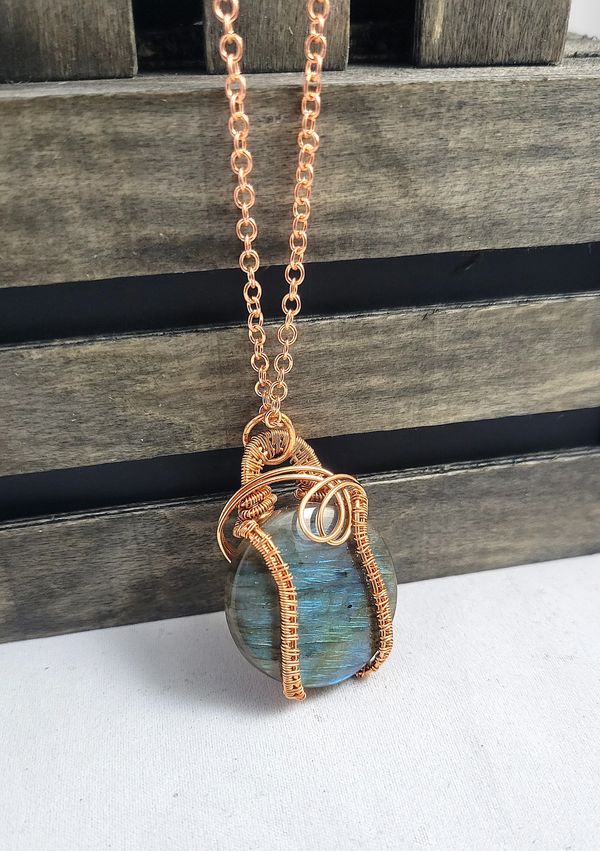 The Eclipse Necklace features a round cabochon Labradorite crystal, wrapped in copper wire.
