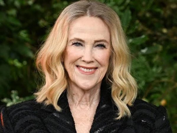Smiling woman with blonde hair in a black outfit.