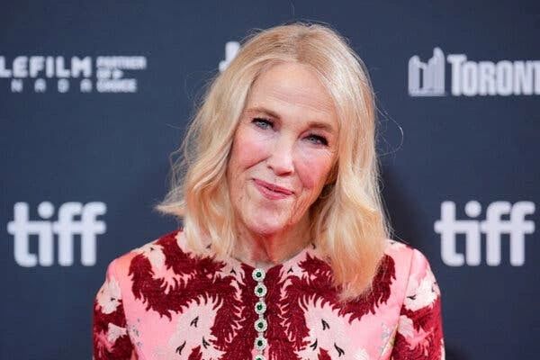 A woman posing at TIFF in a pink and red outfit.