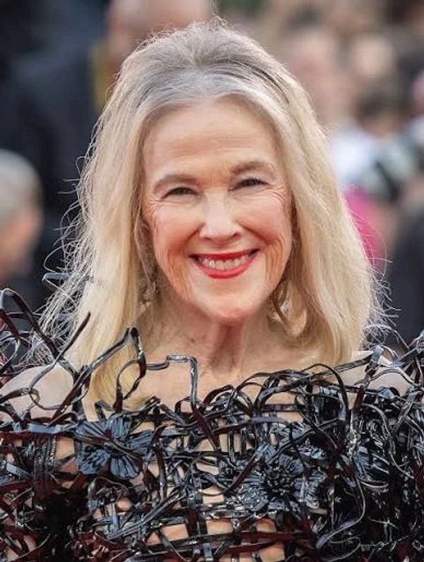 Elderly woman smiling in intricate black dress.
