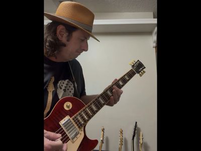 Man in a hat playing electric guitar.
