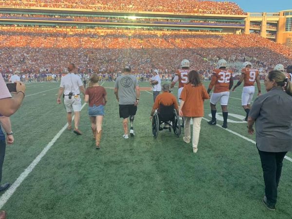 Jacob Schick walking out with Governor Abbott for the coin toss at the Texas vs. LSU game 2019.