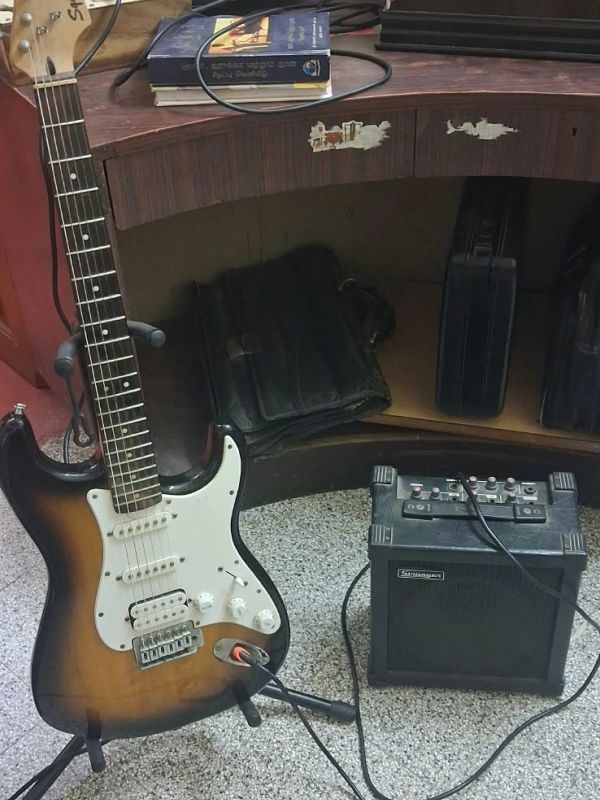 Electric guitar connected to a small amplifier on the floor.
