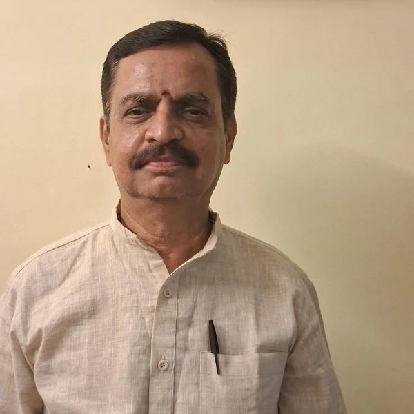 Man with mustache wearing beige traditional shirt.
