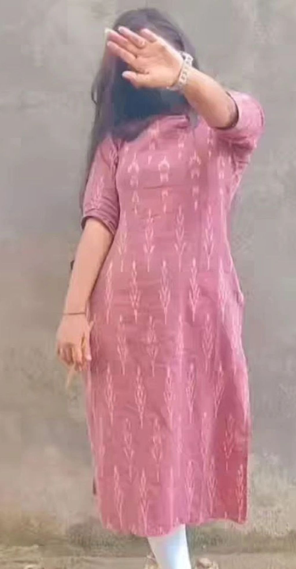 Woman in pink dress covering her face with hand.