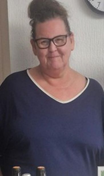 A woman with glasses and a bun hairstyle wearing a navy blue top.