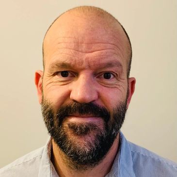 Portrait of a middle-aged man with a beard and a slight smile.