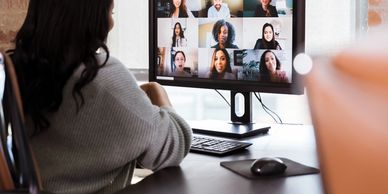 Woman looking at computer monitor with virtual meeting on the screen