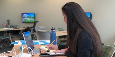 Woman at desk writing on a notepad