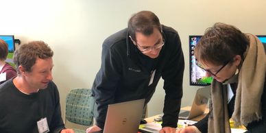 A woman and two men working at a writing retreat