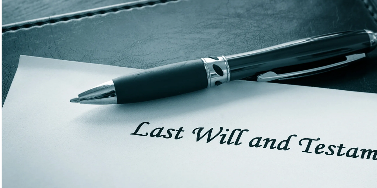 A pen resting on a last will and testament document on a leather folder.