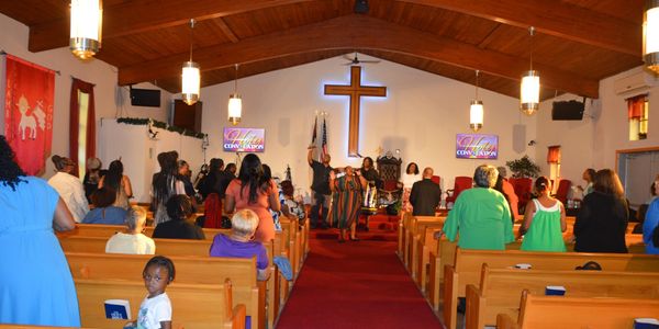 Congregation worships inside a church with a large cross at the altar.