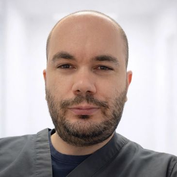 Portrait of a man with a beard in medical scrubs.