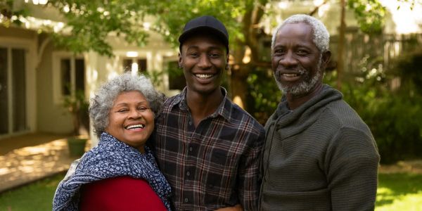 Three generations smiling outdoors in a garden, showing family love.
