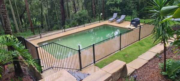 Pool with black aluminium flat top fence.  Sandstone blocks surround the garden.