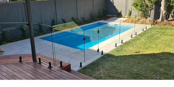 Pool with frameless glass fence.  Timber deck and grassed area in shot.