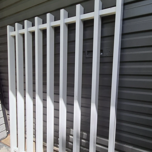White Barr style fence leaning against a Woodland Grey garage door.