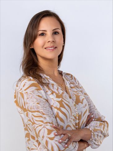 Confident woman with folded arms wearing a patterned blouse.
