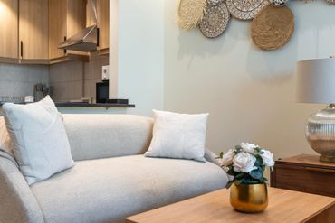 Cozy living room with beige sofa, white pillows, and decorative wall art.