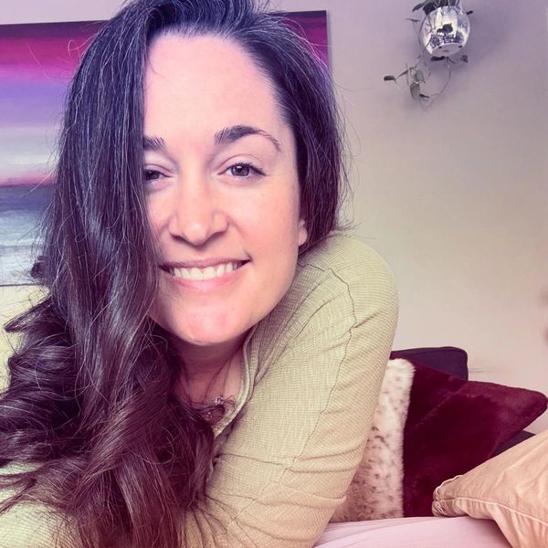 Smiling woman with long dark hair and casual beige sweater.