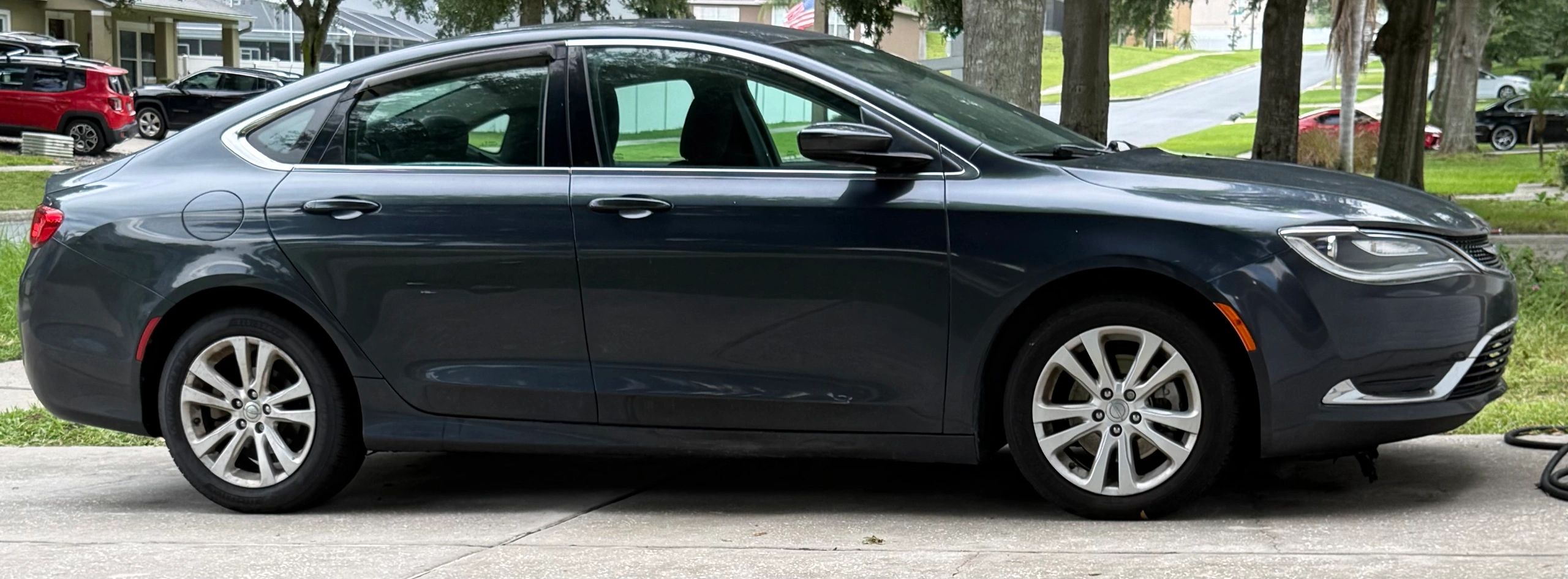Dark gray sedan parked on a driveway in a residential area.