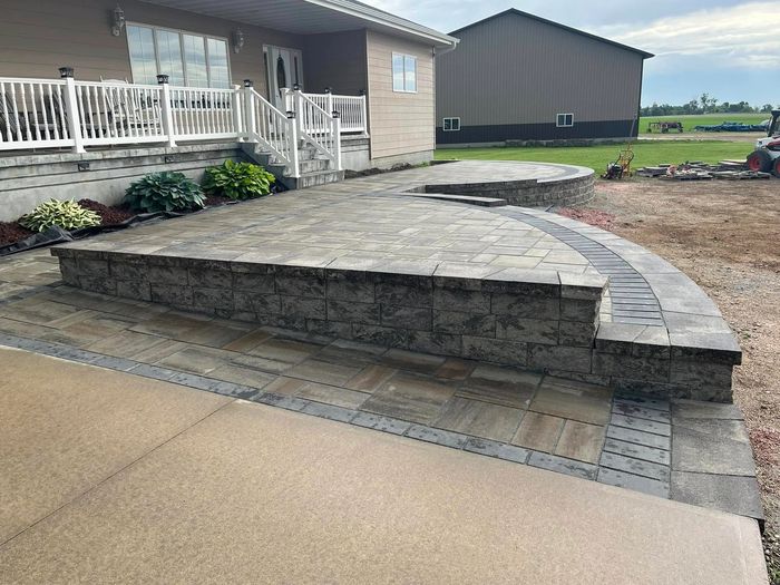 Newly built stone patio and walkway outside a house.