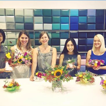 Group of women displaying flower arrangements.