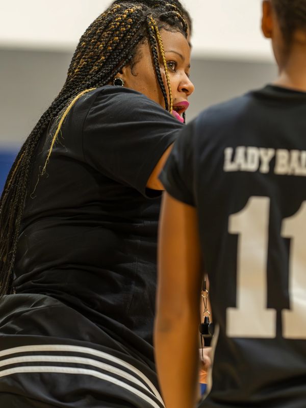 Woman with braided hair coaching basketball player.