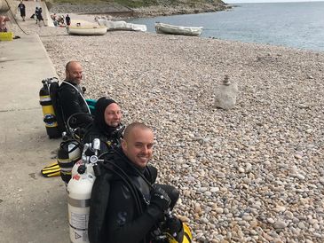 Scuba Diving course in Devon – PADI Insturctor and PADI Open Water students smiling on beach.