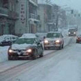 Snow-covered street scene with cars navigating through heavy snowfall and a blurred