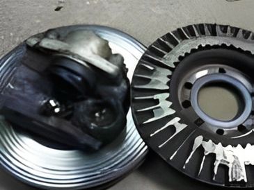 A close-up view of mechanical components: a metal canister and a circular, serrated rotor