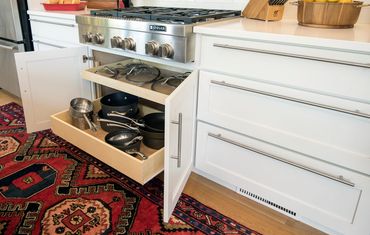 Custom kitchen island with integrated, slide-out trash can cabinet.