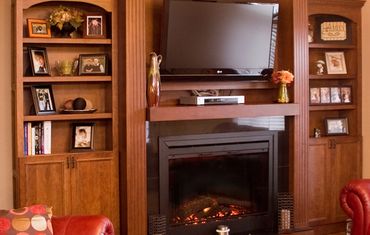 Warm fireplace, custom bookshelves, and wall-mounted television.