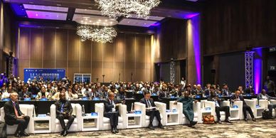 A large audience attending a formal conference in an elegant hall.