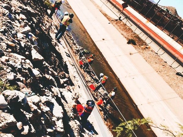 Environmental technicians on a safety line excavating contaminated soils from canal bottom by hand