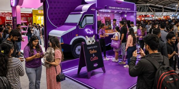 People gather around a purple pet-themed promotional booth at a busy event.