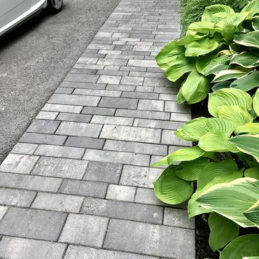 Defined interlocking stone border framing driveway. Adds contrast and boosts curbside appearance.