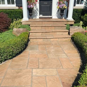 Elegant front entrance with warm-toned natural stone steps, adding curb appeal and durability.