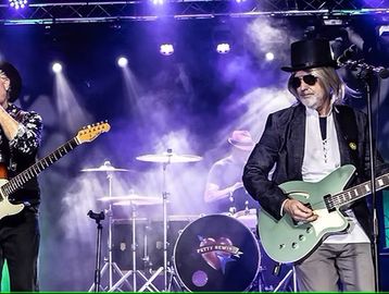 A rock band performs live with vibrant stage lighting and instruments.
