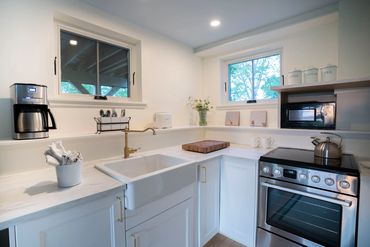 Modern kitchen with white cabinets, brass faucet, and stainless steel stove.